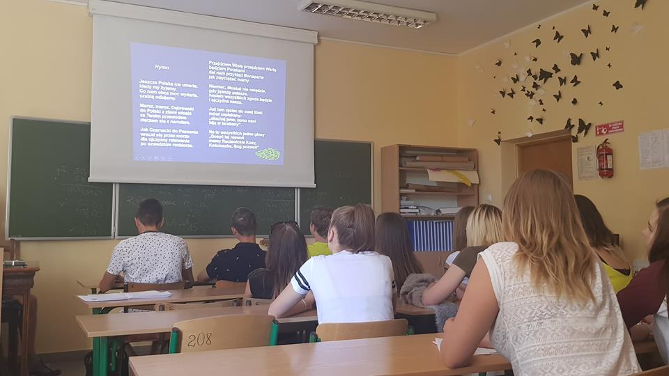 Uczniowie siedzą w ławkach sali lekcyjnej ZSZIO i oglądają przygotowaną prezentację.