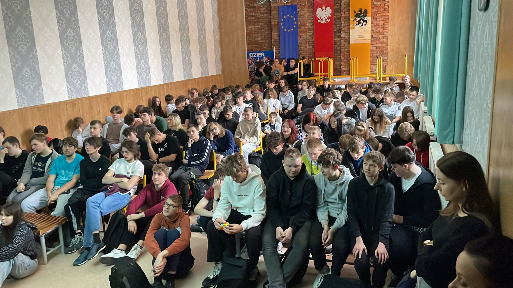 Uczniowie siedzą w auli ZSZiO i oglądają na ekranie webinar.