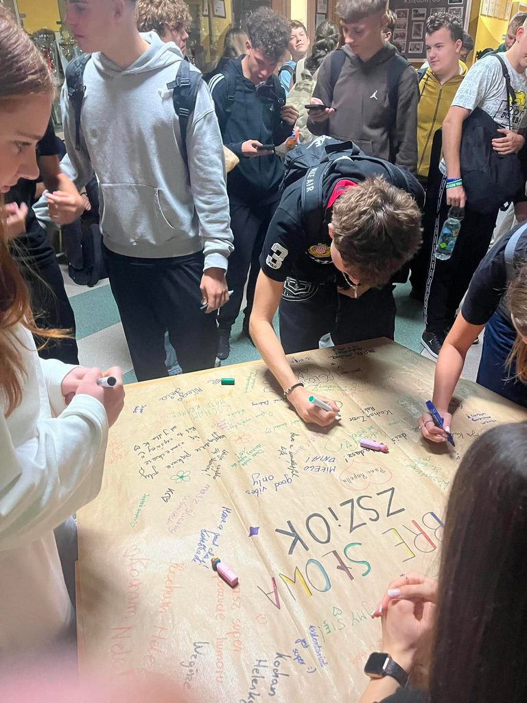 Uczniowie dokonujący wpisu na plakacie